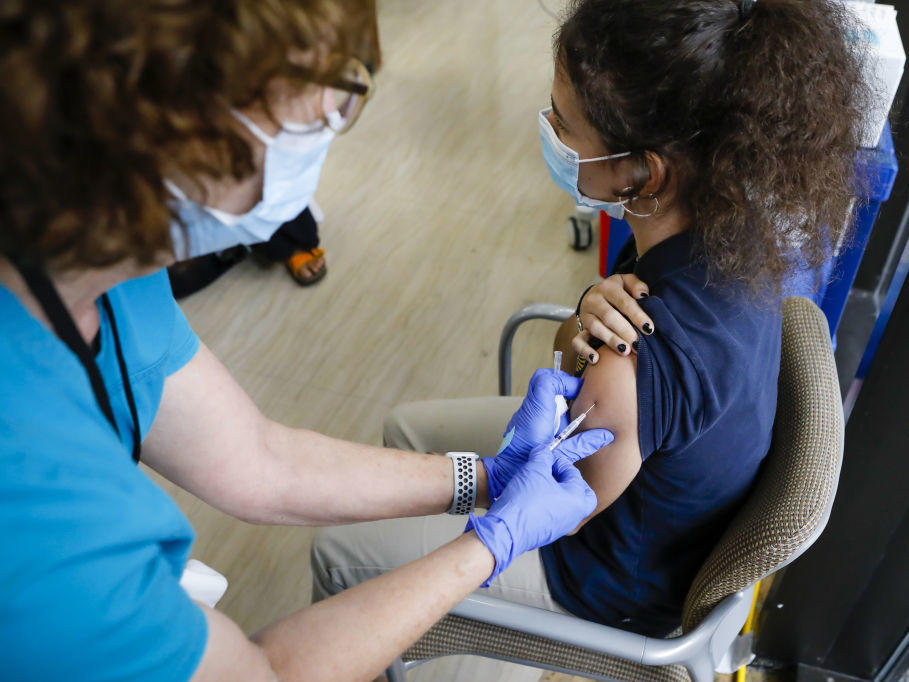 The CDC has softened its guidance for how to operate summer camps for kids this year. Children 12 and older can get the COVID-19 vaccine. Here, a health care worker administers a vaccine dose to a teenager in Miami.