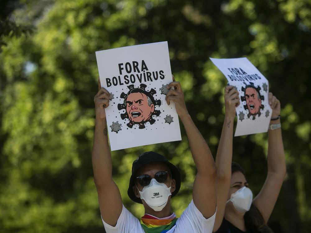 Demonstrators wearing protective face masks hold signs depicting President Jair Bolsonaro as a virus protest against the government's response in combating COVID-19, demanding the impeachment of Bolsonaro, in Rio de Janeiro, Brazil, Saturday, May 29, 2021.