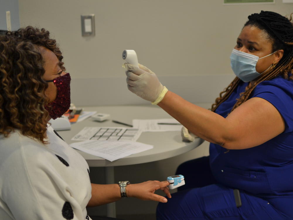 Rotonia Gates, a nurse, checks the temperature of Tonya Beamon of Renova, Miss. on March 3. Beamon decided to get her COVID-19 vaccine at the Delta Health Center because she had heard good things about the staff.