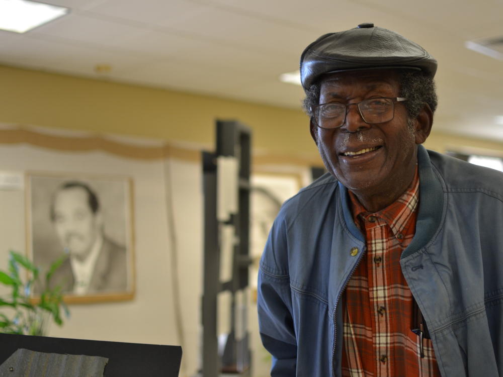 Mitch Williams, 85, grew up in Mound Bayou and became a patient after Delta Health Center opened. He later got a job at the health center and now serves on the clinic's Board of Directors. He was photographed in an exhibit of the clinic's history, near a portrait of Andrew James, who was the center's director of environmental improvement.