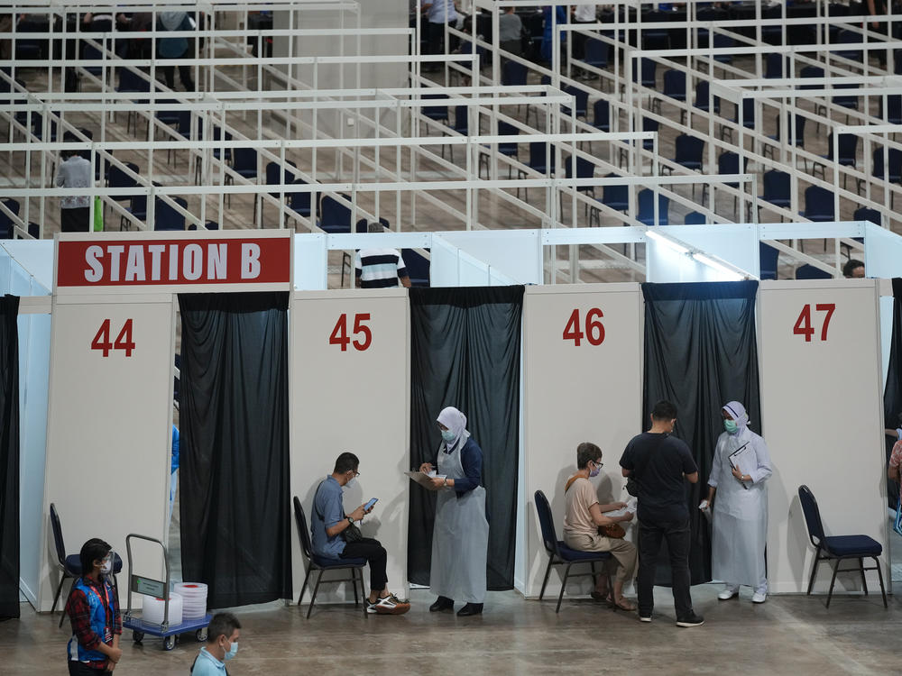 Health staff and patients at an exhibition center in Kuala Lumpur that's been turned into Malaysia's first mega-vaccination center. The government aims to speed up inoculations amid a sharp spike in infections.