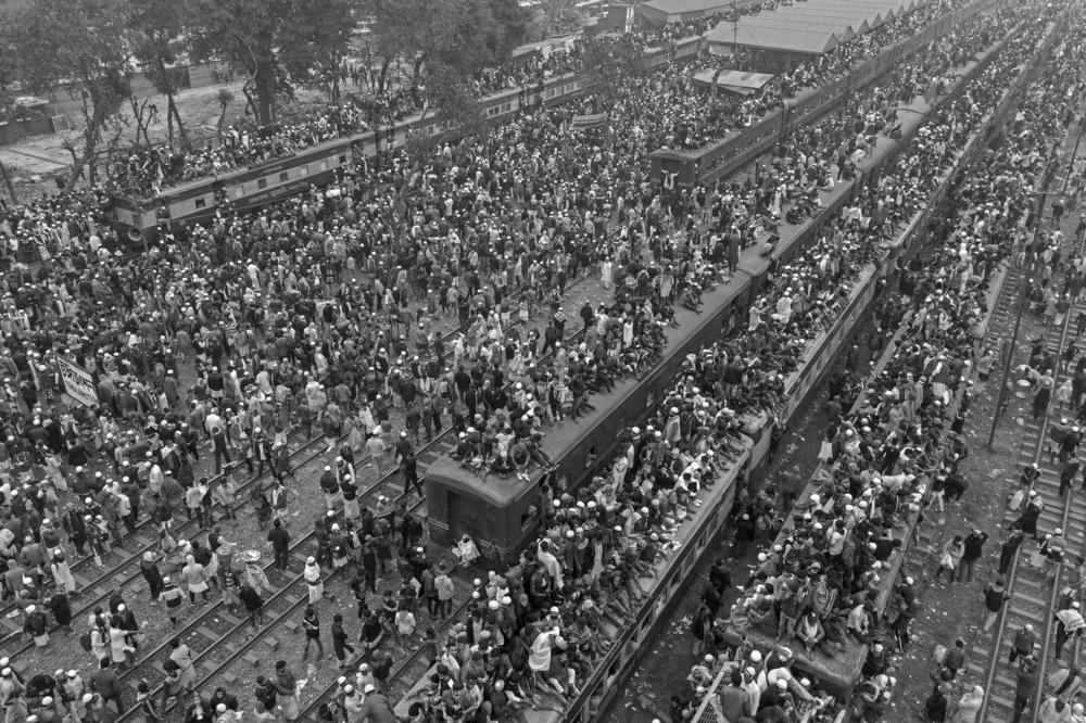 Thousands of commuters and travelers board a train in Tongi, Bangladesh. There aren't enough seats — or trains — for the thousands of travelers. So people look for any way to ride and get home, grabbing onto the outside of the train and even standing on the roof.