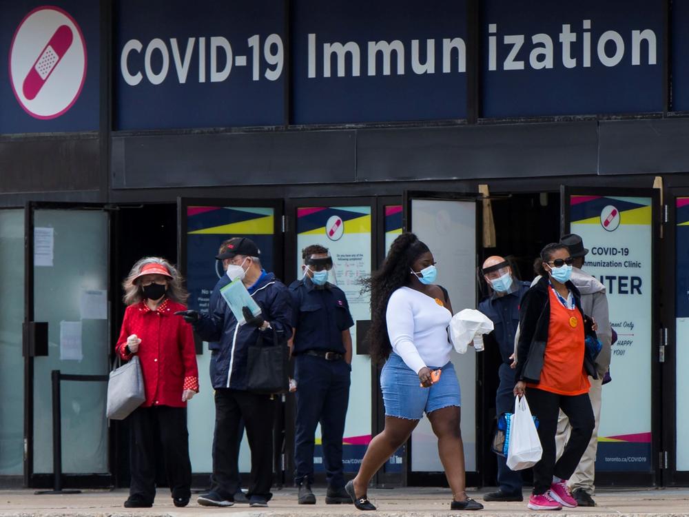 Canada's National Advisory Committee on Immunization is recommending allowing people to mix COVID-19 vaccine doses. Here, people walk past a vaccination clinic this week in Toronto.