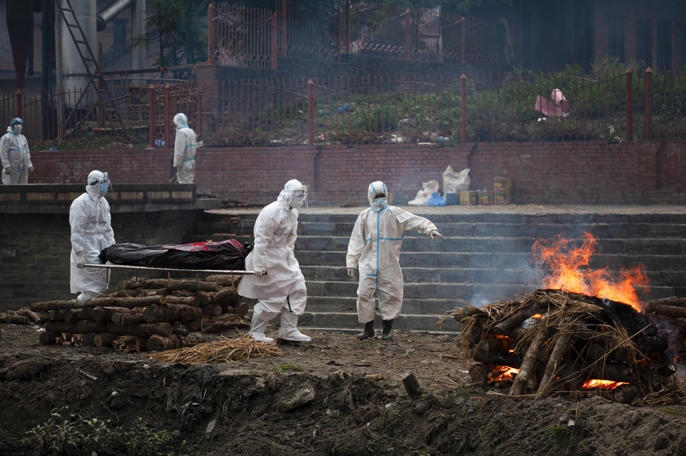 Workers in protective gear carry the body of a person who died of COVID-19 or cremation on the bank of Bagmati River in Kathmandu. As a wave of infections sweeps Nepal, the only crematorium in Kathmandu Valley is struggling to cope with the flow of bodies.