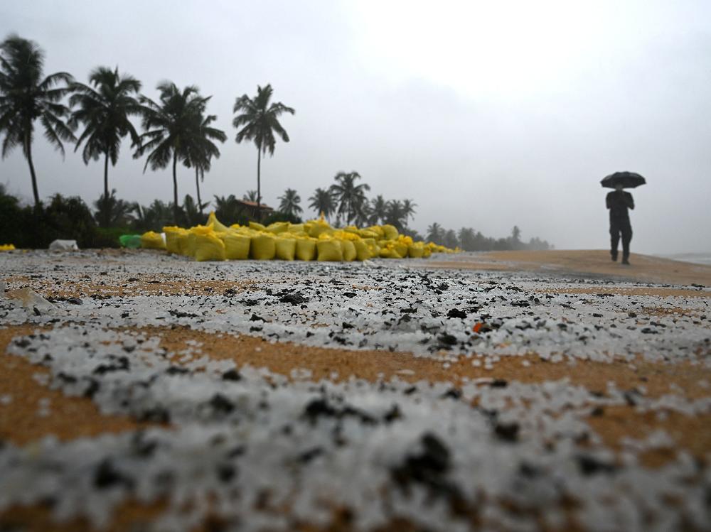 A man walks past sacks containing debris washed ashore from the X-Press Pearl on a beach in Colombo on Thursday. The plastic pellets will break down and be more difficult to clean up over time, marine biologist Asha de Vos says.
