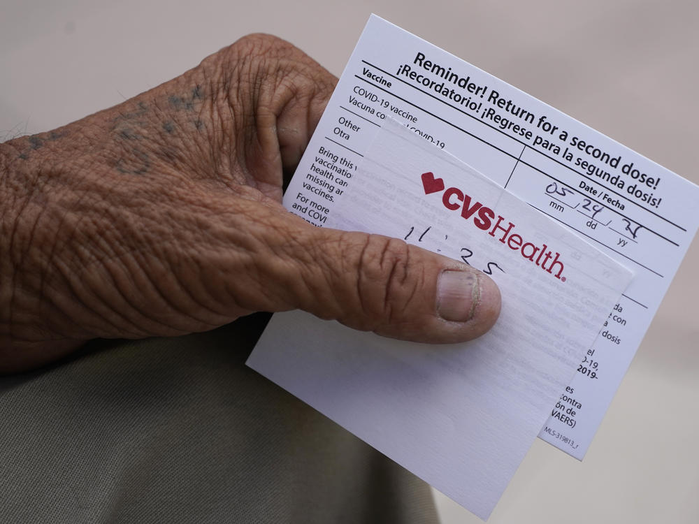 A man holds his vaccination reminder card after having received his first shot at a pop-up vaccination site next to Maximo Gomez Park, also known as Domino Park, on May 3 in the Little Havana neighborhood of Miami.