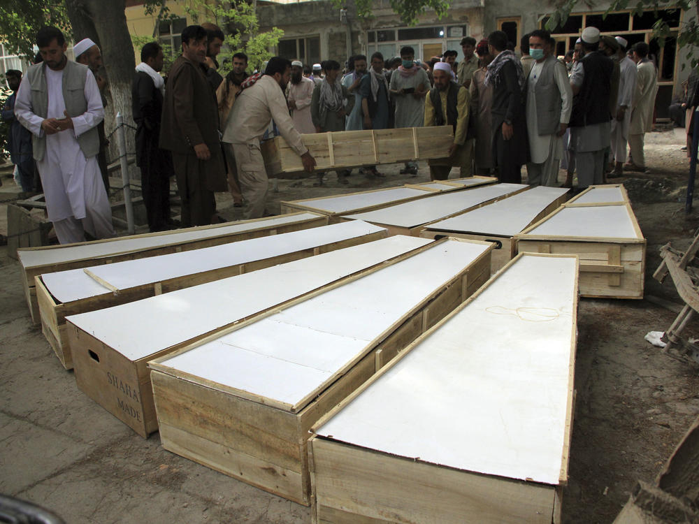 The coffins of the victims in Tuesday's attack are placed on the ground at a hospital in northern Baghlan province, Afghanistan, on Wednesday. Workers of the HALO Trust demining organization were attacked on Tuesday night by armed gunmen.