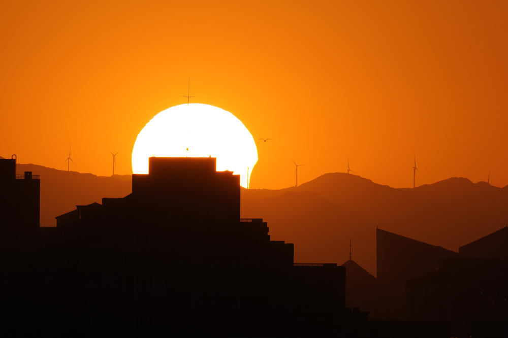 The sun is partially eclipsed as it sets over the horizon in Beijing.