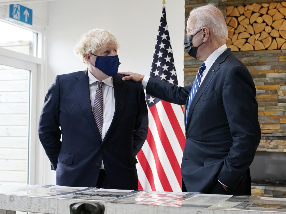 British Prime Minister Boris Johnson and President Biden talk Thursday during a meeting in Carbis Bay, England, as they look over copies of the original Atlantic Charter from 1941.