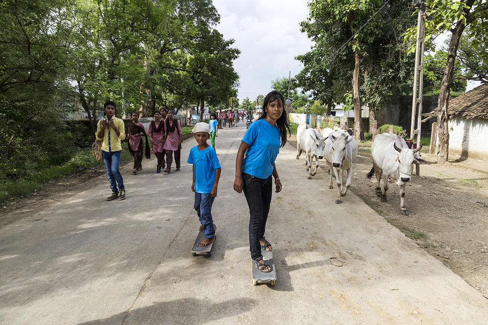 Asha Gond (center right) rides her skateboard. When she first began skateboarding, neighbors would catcall that skateboarding is for boys and urge her parents to marry her off.