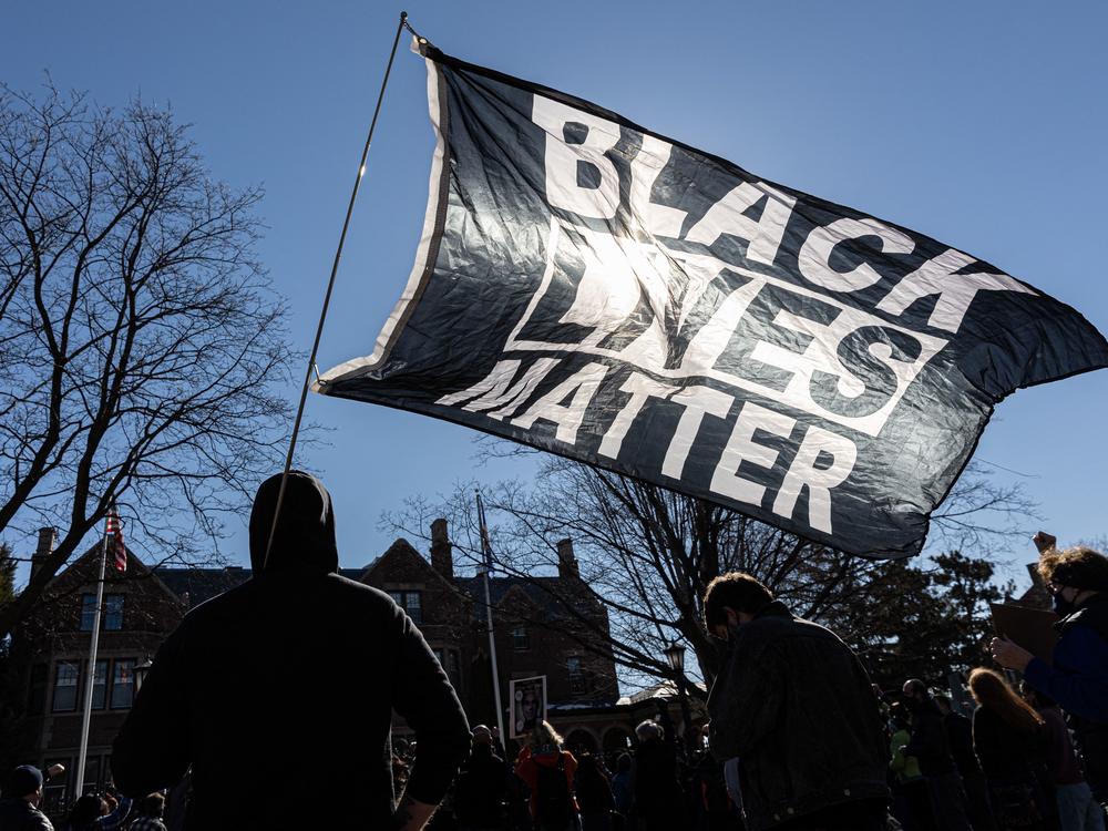 A man holds a Black Lives Matter flag during a protest in St. Paul, Minn., in March shortly before the start of Derek Chauvin's trial in George Floyd's killing.