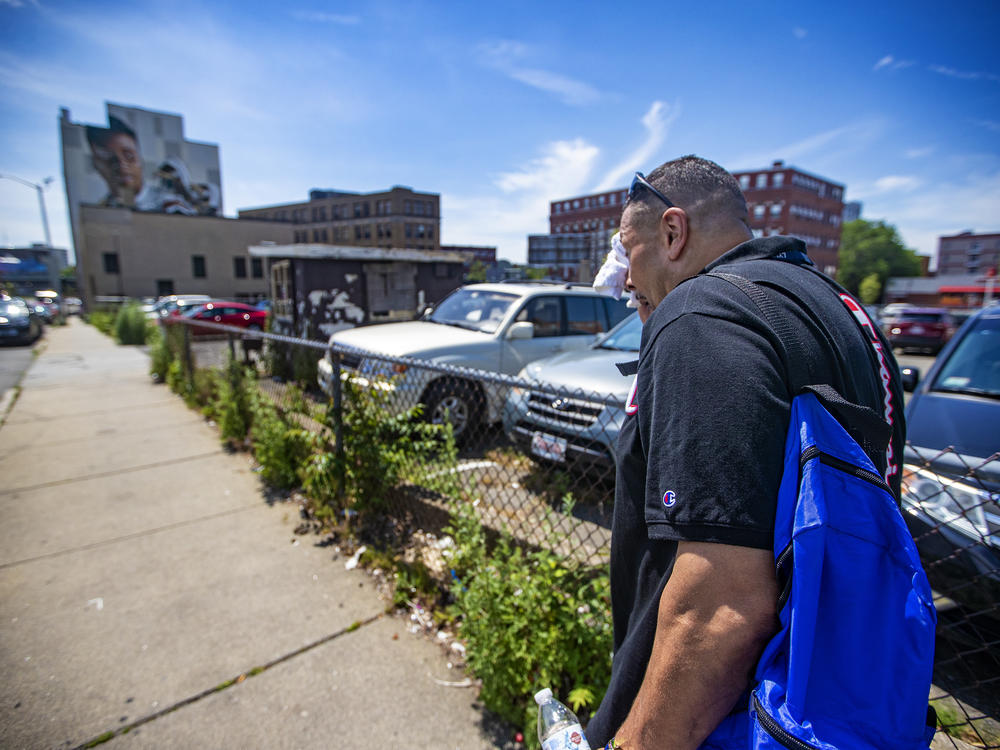 Will wipes away sweat on a hot day while walking down Willow Street in Lynn, Mass., as he looks to distribute safety supplies to drug users on the street.