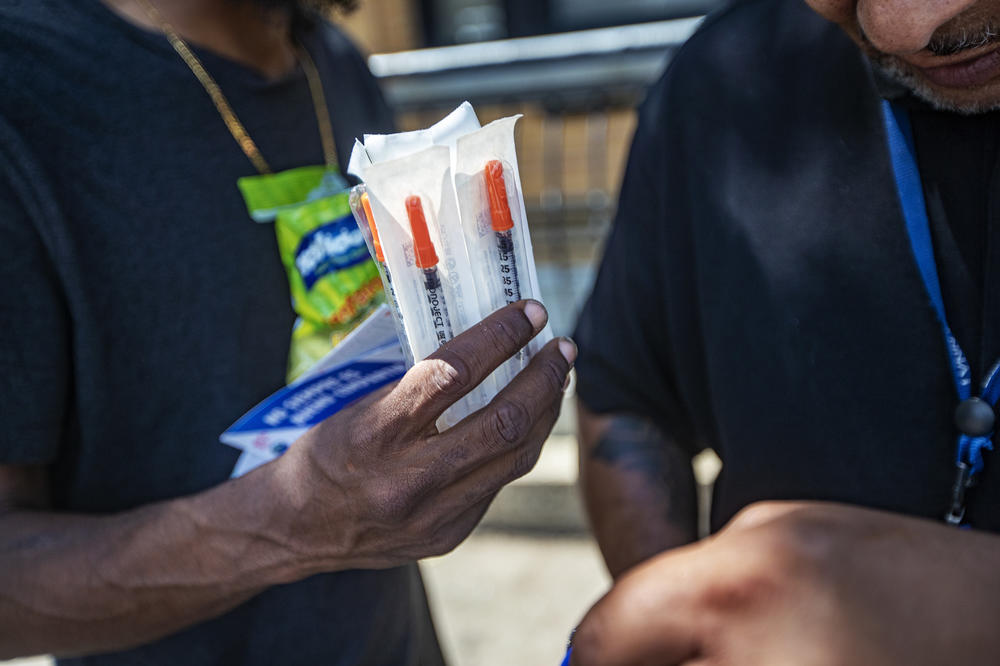 Will distributes new sterile syringes to a drug user in front of the My Brother's Table soup kitchen in Lynn, Mass.