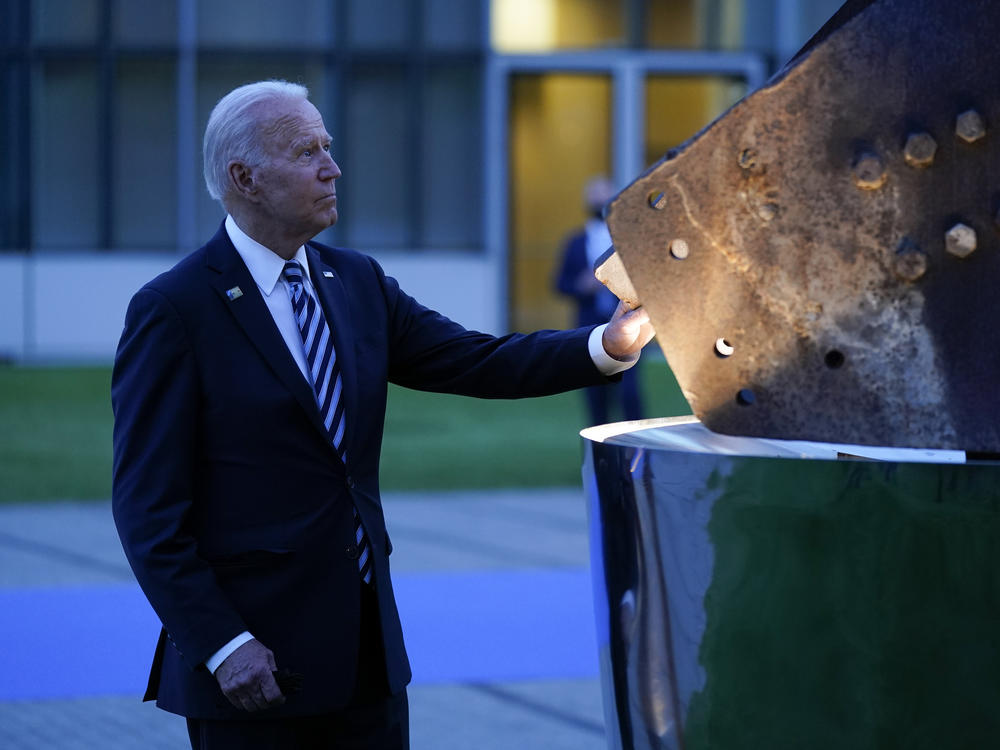 President Biden touches a piece of steel from the World Trade Center at a memorial to the 9/11 attacks Monday at NATO headquarters in Brussels. NATO allies joined in a collective defense with the U.S. after the terror attacks.