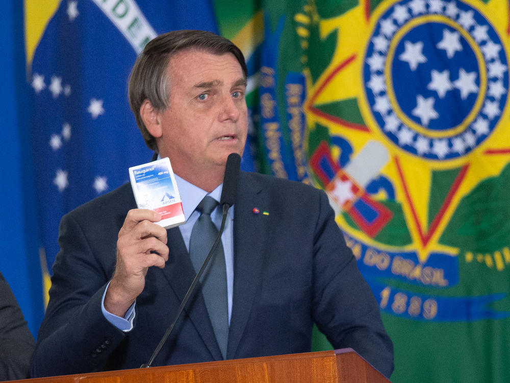 Brazilian President Jair Bolsonaro holds up a box of chloroquine, an antimalarial medicine that his administration endorsed as part of an 