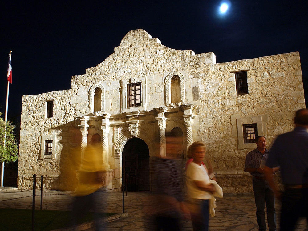 Visitors walk around the outside of the Alamo in San Antonio.