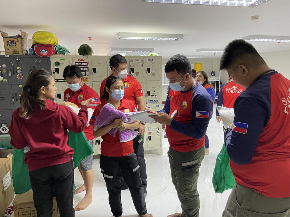 Staffers distribute the required personal protective gear before they transfer a COVID-positive patient to a hospital. They'll wear a gown, gloves, mask and face shield.