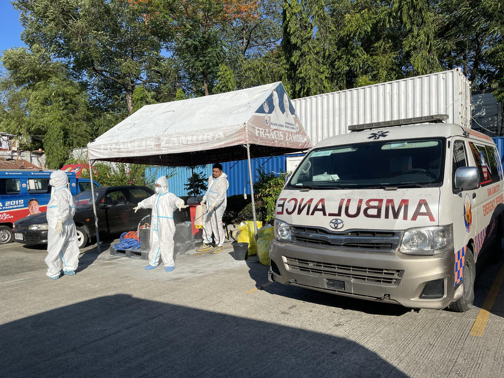 Team members of the San Juan City Early Response Network decontaminate after transferring a COVID-positive patient from their home to Philippine General Hospital.