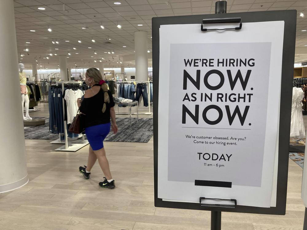 A customer walks behind a sign at a Nordstrom in Coral Gables, Fla., store seeking employees in May.