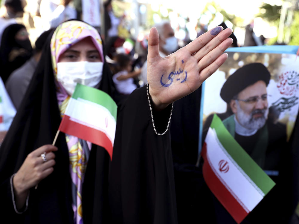 A supporter of presidential candidate Ebrahim Raisi shows her hand with writing in Persian that reads 