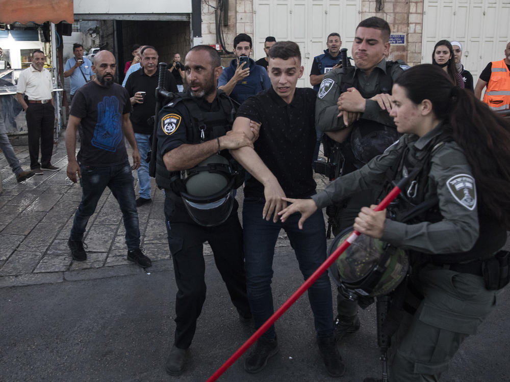 Police officers clash with a Palestinian man as they force Palestinians out of the Damascus Gate area before the far-right flag march Tuesday in Jerusalem.