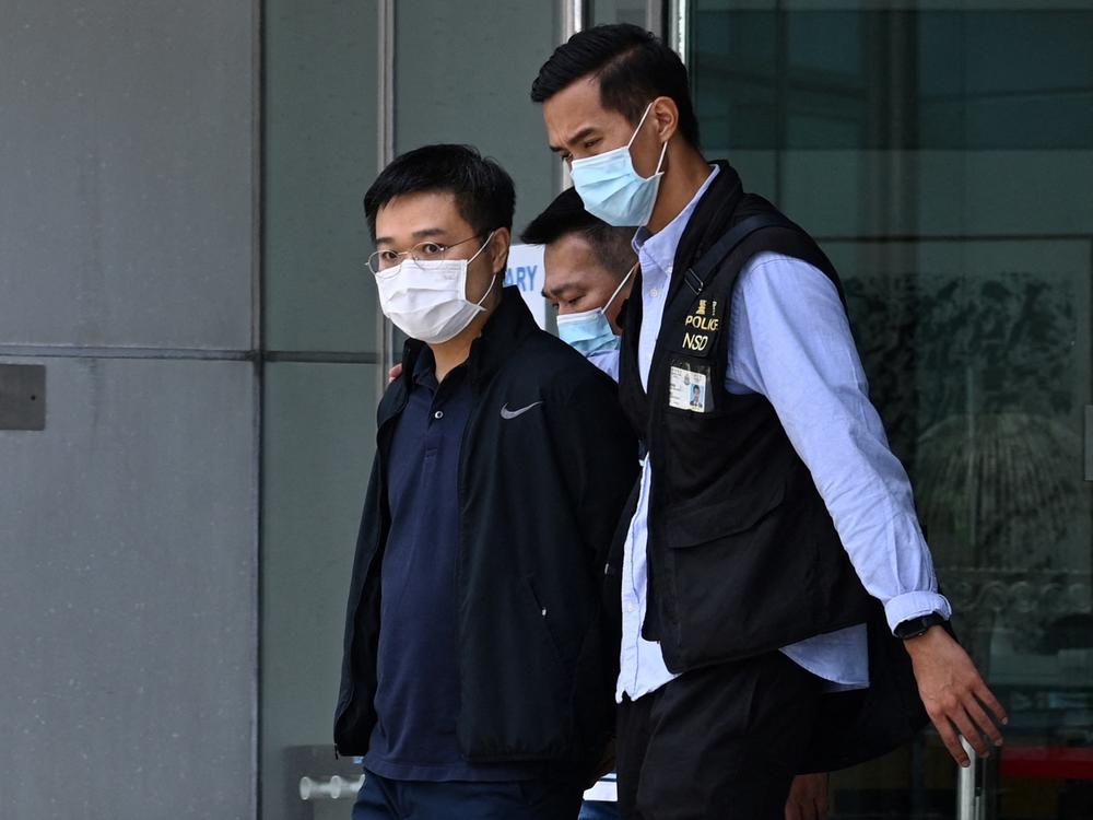 Apple Daily editor-in-chief Ryan Law is escorted by police to a waiting vehicle outside the entrance of the Apple Daily newspaper offices in Hong Kong on Thursday.