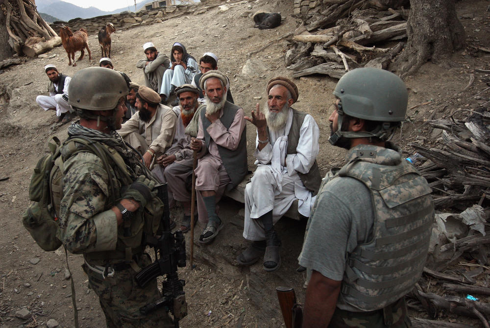 Village elders speak with a U.S. Marine through an interpreter as American and Afghan forces search for weapons in the Korengal Valley of Kunar Province in eastern Afghanistan in 2008.