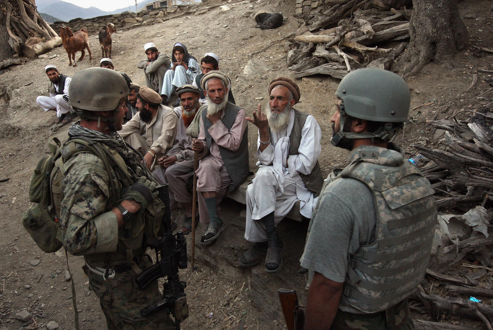 Village elders speak with a U.S. Marine through an interpreter as American and Afghan forces search for weapons in the Korengal Valley of Kunar Province in eastern Afghanistan in 2008.