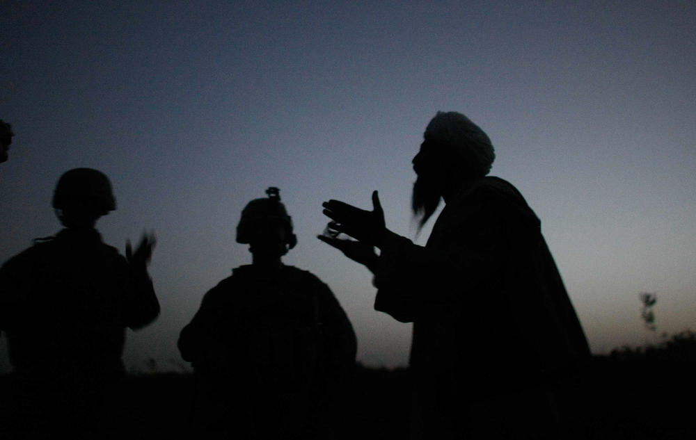 Marine Sgt. Nathan Harris speaks to an Afghan man through an interpreter after seeing suspicious activity near their base in Mian Poshteh, Afghanistan, in 2009.