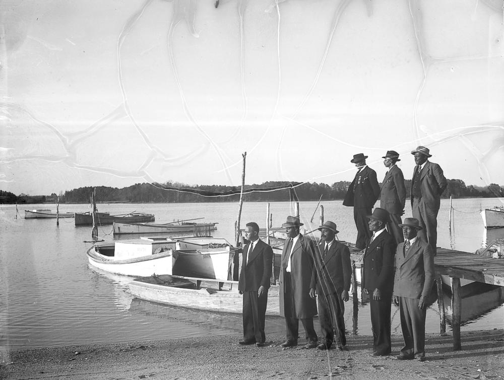 Men gather near a dock.
