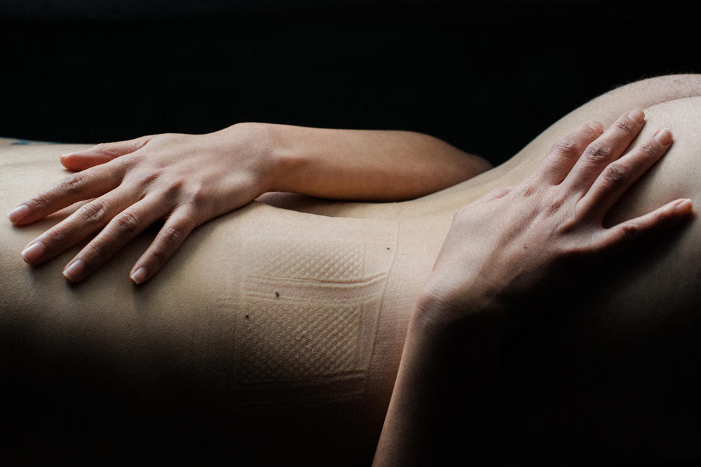 The photographer's partner embraces their body, still marked with the indentation of a corset.