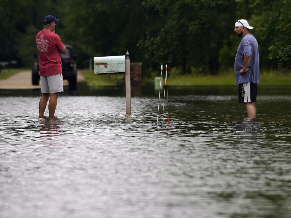 Danny Gonzales (right) stands in front of his flooded house with his neighbor Bob Neal after Tropical Storm Claudette passed through, in Slidell, La., on Saturday.