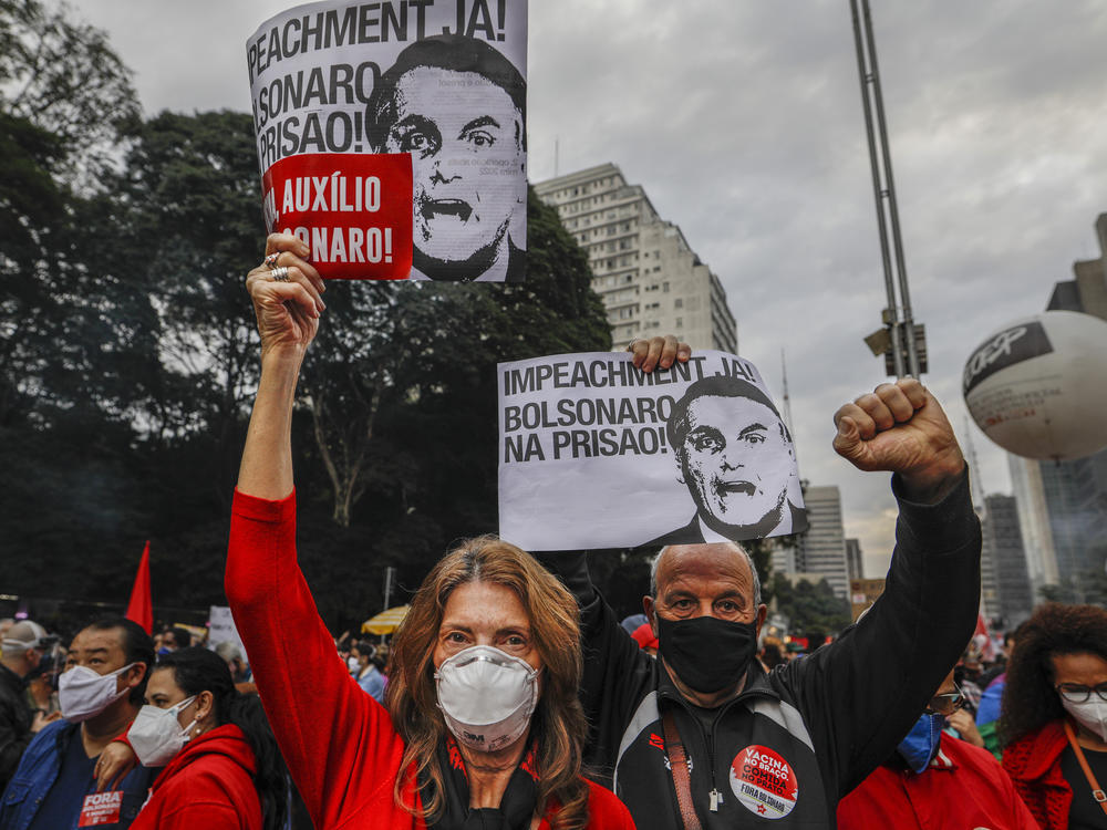 Demonstrators hold signs that read in Portuguese: 