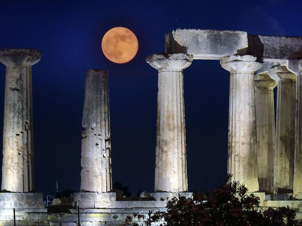 June's full moon, known as the strawberry moon, was named for its appearance during the strawberry picking season. Here, the strawberry moon rises above the Apollo Temple in ancient Corinth, on June 17, 2019.