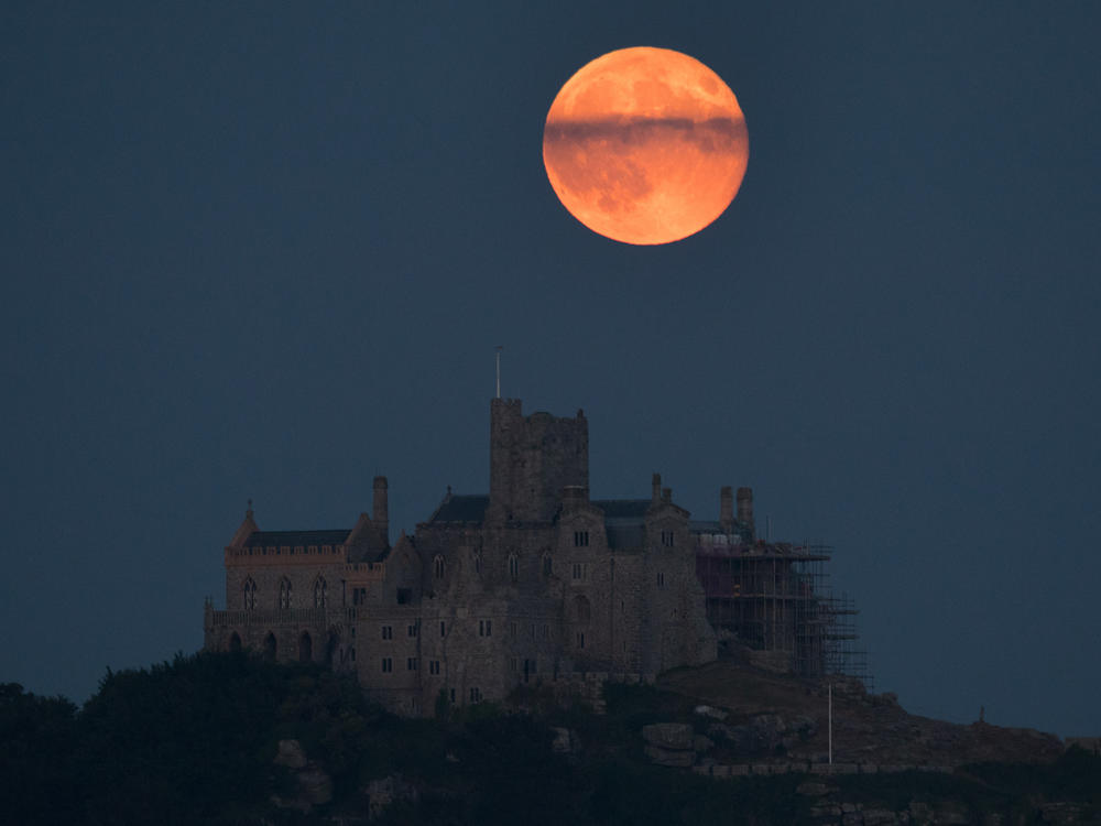 While in some circumstances the strawberry moon can temporarily appear reddish or pinkish, it is named for the start of the strawberry picking season, and not the color. Here, a strawberry moon rises behind St. Michael's Mount in Marazion near Penzance on June 28, 2018 in Cornwall, England.