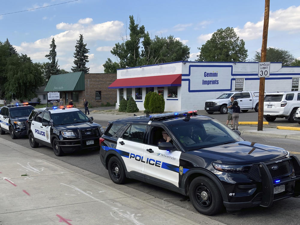 Police cars line up for a procession in honor of an officer who was fatally shot Monday in Arvada, Colo.