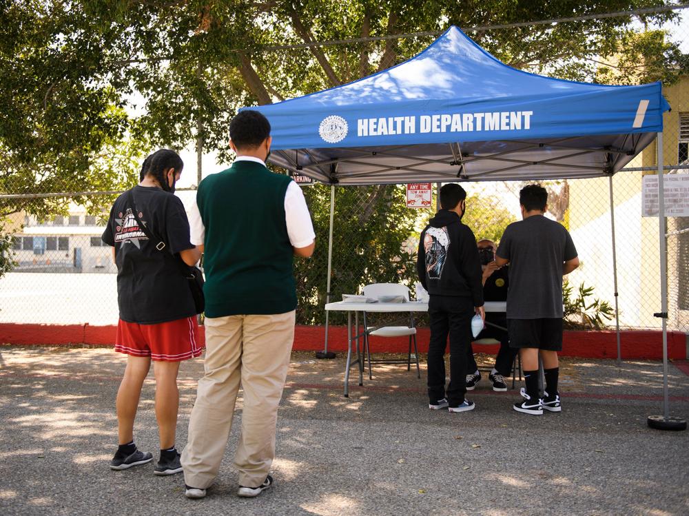 Teenagers get vaccination cards after receiving a first dose of the Pfizer COVID-19 vaccine last month at a mobile clinic at the Weingart East Los Angeles YMCA in Los Angeles.