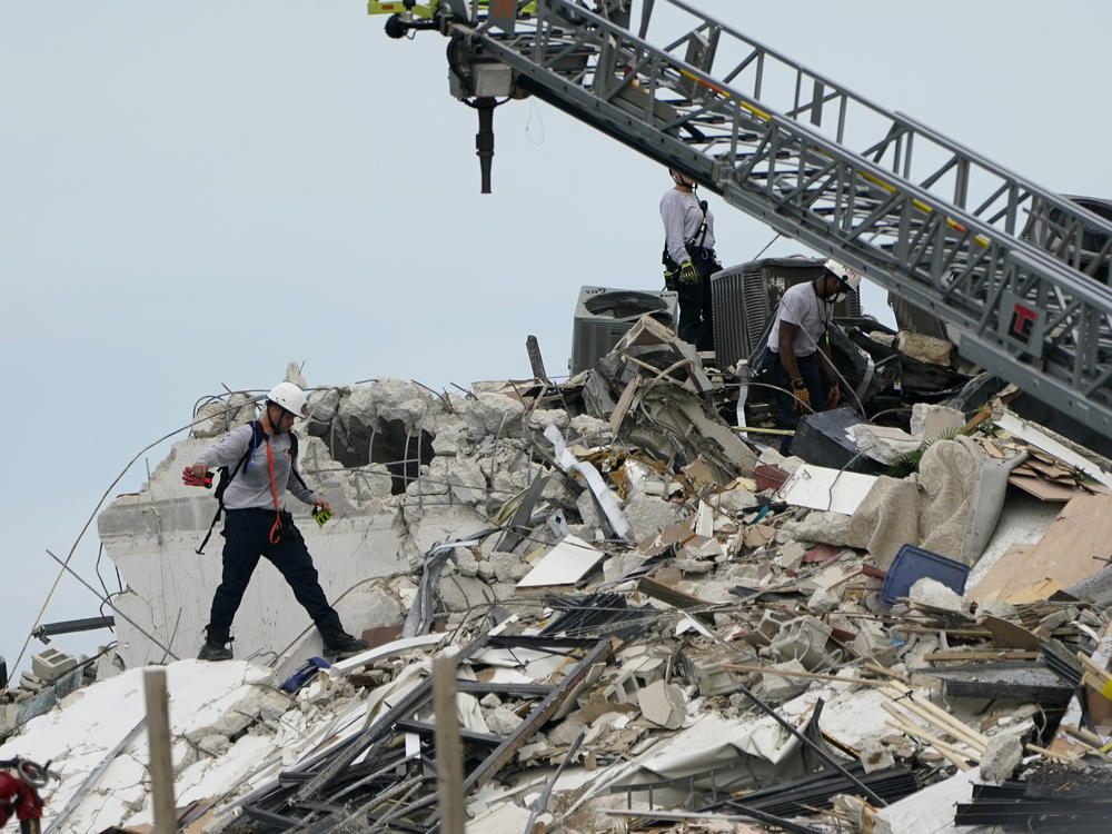 Rescue workers walk atop the rubble of a 12-story beachfront condo building that partially collapsed in Florida's Miami-Dade County.