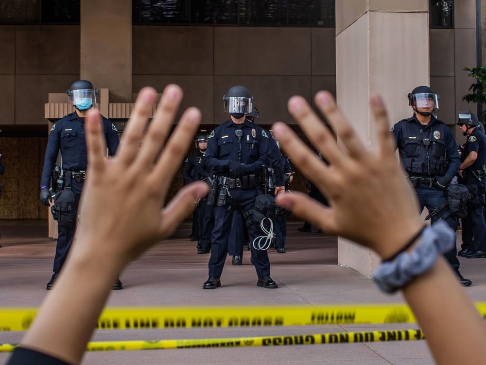 A demonstrator holds her hands up while she kneels in front of the Police at the Anaheim City Hall on June 1, 2020 in Anaheim, California. Reform pressures have many cops leaving the job.