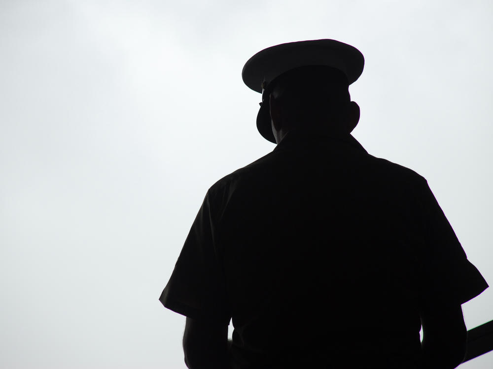 Silhouette of a U.S. Marine praying, photographed from behind.