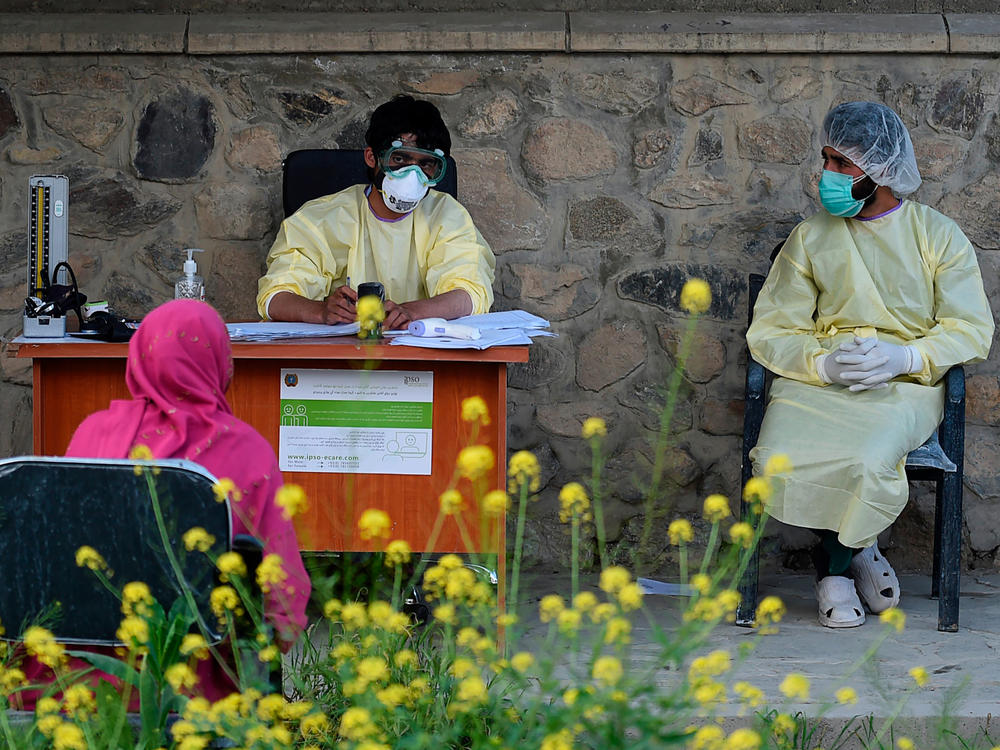 Medical staff wearing personal protective equipment register a suspected coronavirus patient in May at a Kabul hospital.