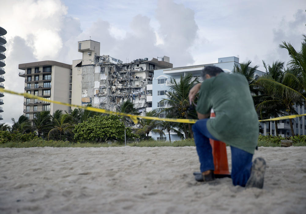 A man prays near where search and rescue operations continue at the site of the Champlain Towers South condo building on Friday. The man, overcome with emotion, said he had lost a relative in the collapse.