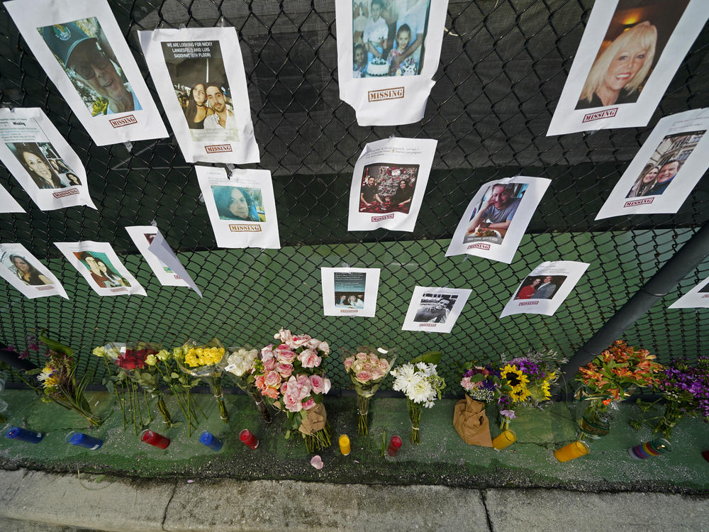 A memorial near the Champlain Towers disaster site holds photos of missing persons in Surfside, Fla. Rescuers continue their search for survivors, but have confirmed that nine people are dead and more than 150 are still missing.