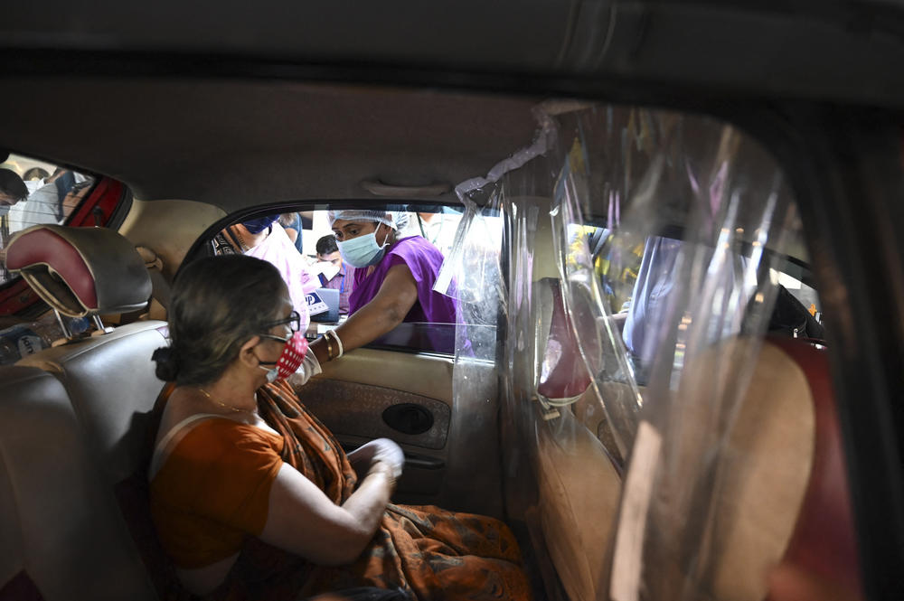 A health worker inoculates a woman with a dose of the Covishield vaccine at a drive-in vaccination center on a shopping mall parking lot in Kolkata on June 4.