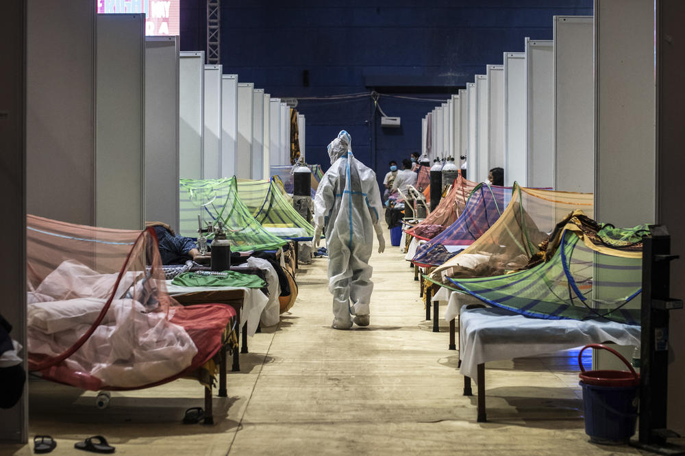 A medical worker observes COVID-19 patients in a sports stadium converted into a care facility. At the peak of the pandemic in India, there were over 400,000 cases — and 4,500 deaths — a day. Numbers are now starting to decline.