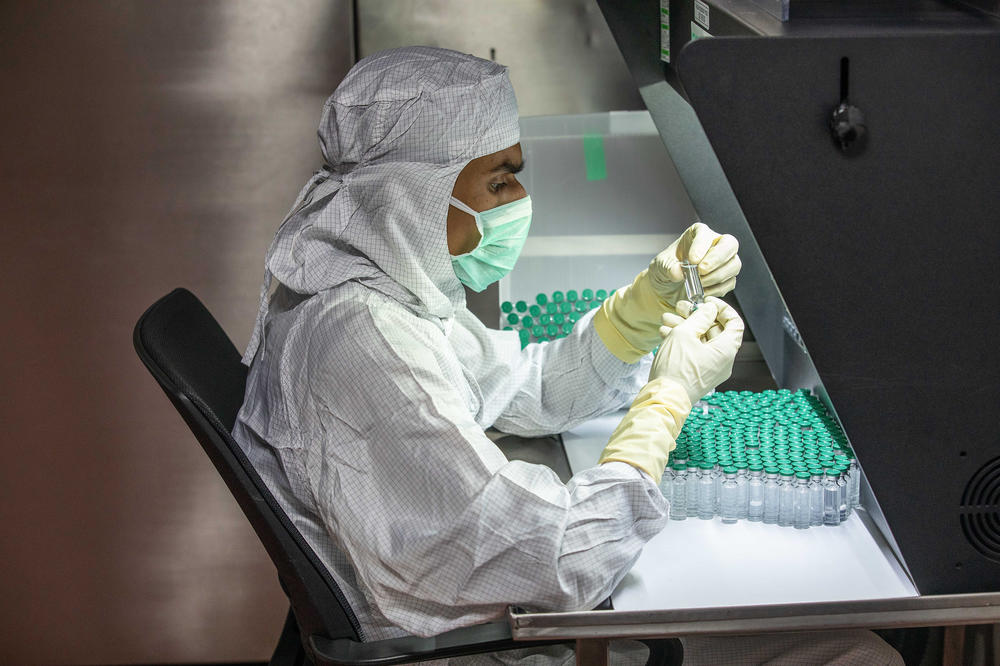 A technician at the Serum Institute checks for any deficiencies in vaccine doses and vials.