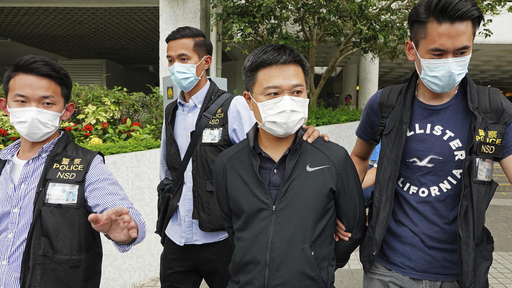 Ryan Law (second from right), <em>Apple Daily</em>'s chief editor, is arrested by police officers in Hong Kong on June 17. He and executives at the newspaper were arrested under the national security law on suspicion of collusion with a foreign country to endanger national security.