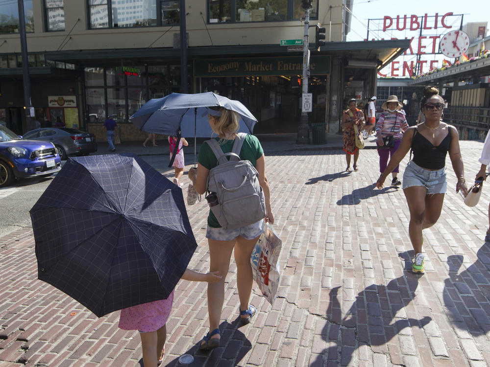 Seattle reached 108 degrees on Monday during the heat wave in the Pacific Northwest. Here, a mother and daughter carry umbrellas to shield from the sun.