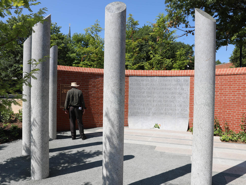 A visitor stands Monday by a new memorial dedicated to the five people who died in the mass shooting at the <em>Capital Gazette</em> three years ago in Annapolis, Md. The five pillars honor Rebecca Smith, Wendi Winters, Gerald Fischman, Rob Hiaasen and John McNamara who died in the attack. The memorial includes the First Amendment in a panel.