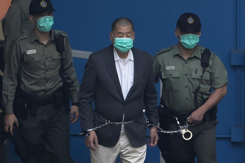 Jimmy Lai, who founded the <em>Apple Daily</em> newspaper, is escorted by correctional officers to a prison van before appearing in a court in Hong Kong on Dec. 12, 2020. After editors and executives at the paper were arrested and its financial assets were frozen, <em>Apple Daily</em> closed down in June.